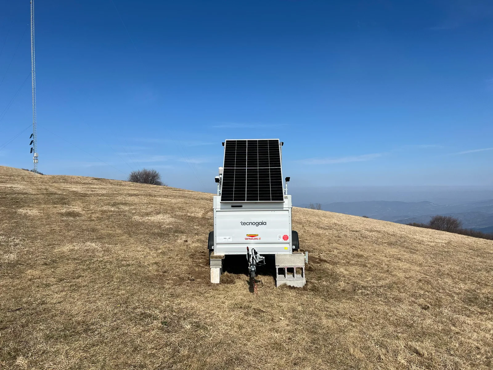 Trailer con profilatore LiDAR e pannello solare in cima a un crinale, cielo terso